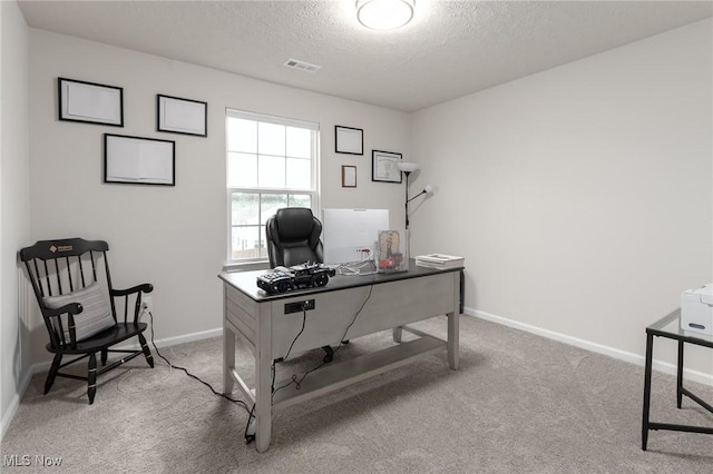 carpeted office featuring visible vents, a textured ceiling, and baseboards