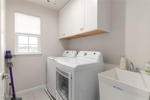 washroom with light tile patterned flooring, a sink, visible vents, washer and dryer, and cabinet space