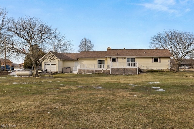 rear view of property with an attached garage, a chimney, and a lawn