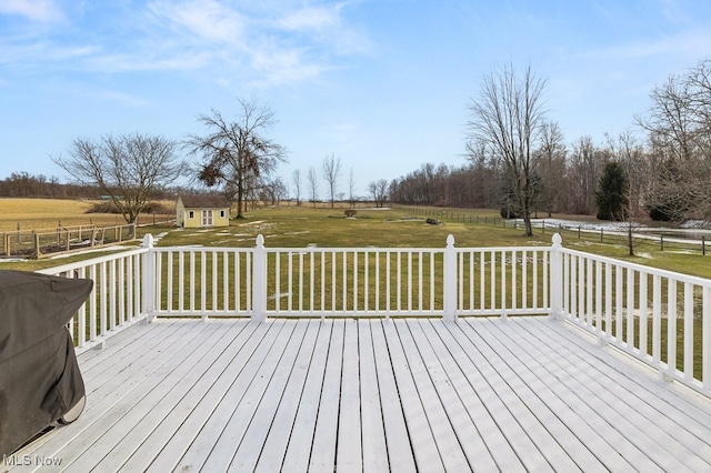 wooden terrace with a rural view, a lawn, an outdoor structure, and fence