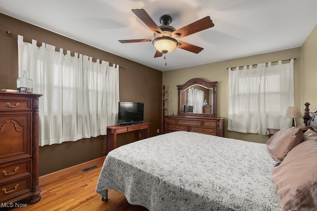 bedroom featuring a ceiling fan, visible vents, and light wood finished floors