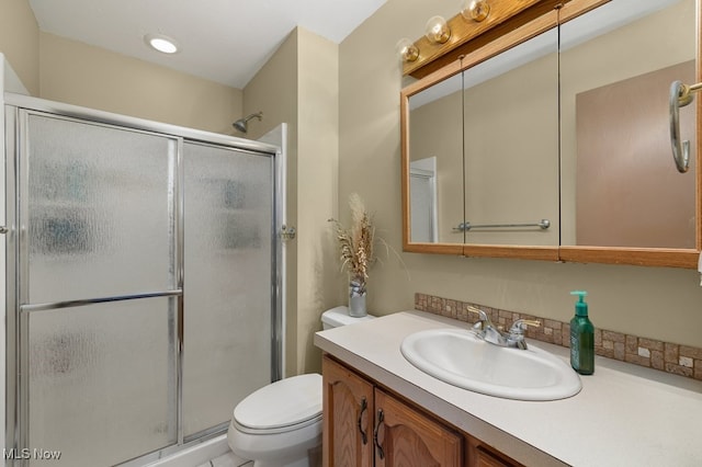 bathroom with toilet, a shower with shower door, and vanity