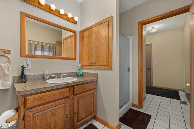 bathroom with tile patterned flooring, a shower stall, vanity, and baseboards