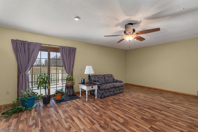 sitting room with a ceiling fan, a textured ceiling, baseboards, and wood finished floors