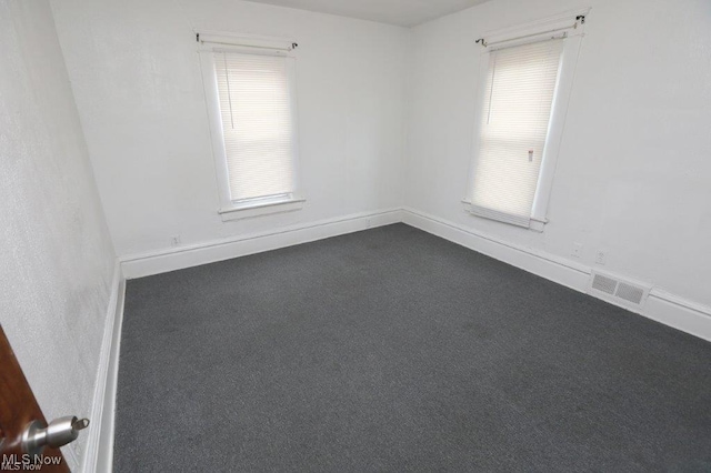 unfurnished room featuring baseboards, visible vents, and dark colored carpet