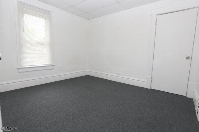 carpeted empty room featuring a paneled ceiling