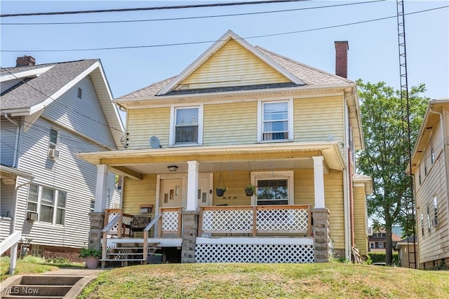 traditional style home with covered porch, a shingled roof, a chimney, and a front yard