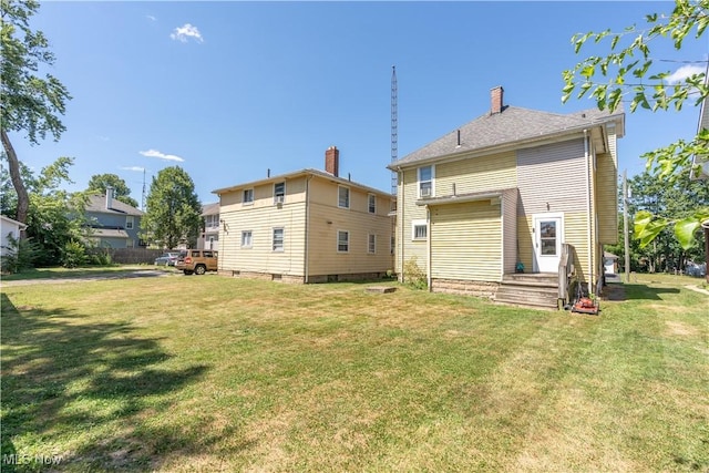 rear view of house featuring a chimney and a yard