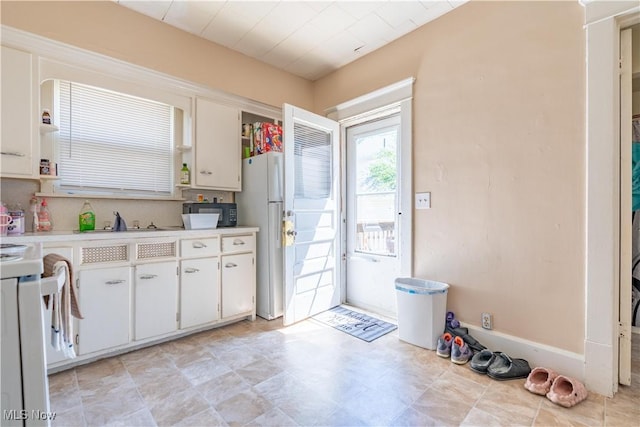 kitchen featuring open shelves, light countertops, freestanding refrigerator, white cabinetry, and black microwave