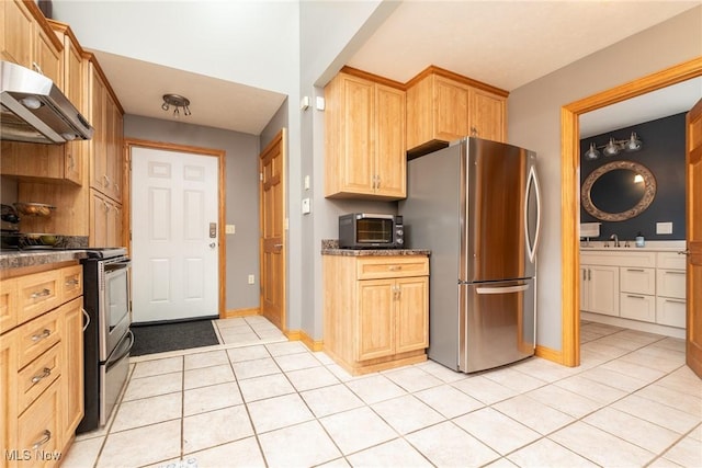 kitchen with light tile patterned flooring, under cabinet range hood, a sink, appliances with stainless steel finishes, and light brown cabinetry