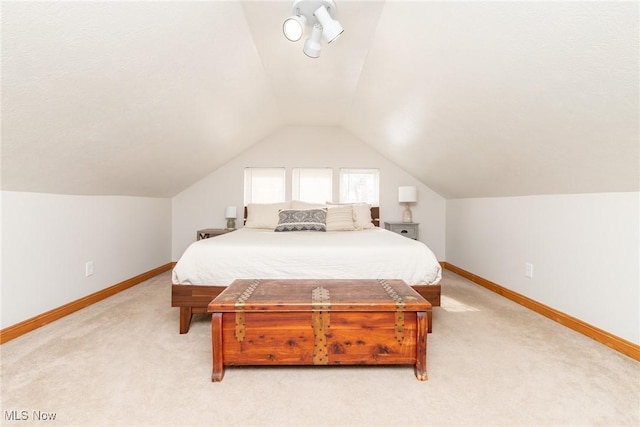 bedroom with light carpet, baseboards, and vaulted ceiling