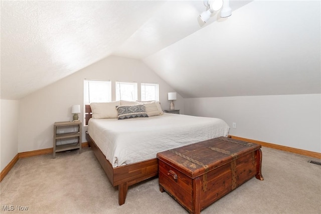 bedroom with lofted ceiling, light carpet, a textured ceiling, and baseboards