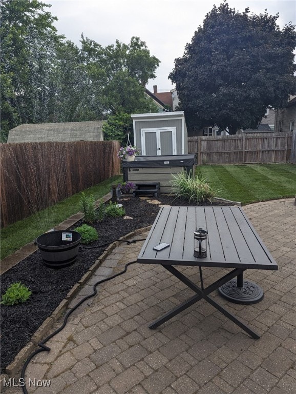 view of patio / terrace featuring a storage shed, an outdoor structure, a fenced backyard, and a hot tub