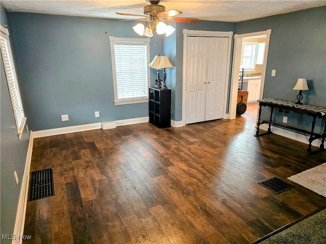 bedroom with a closet, dark wood-style flooring, visible vents, and baseboards