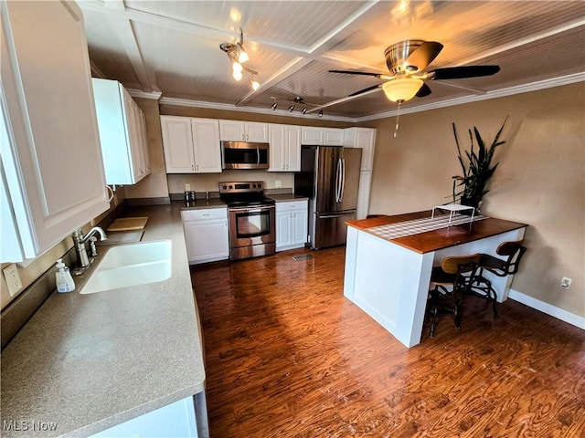 kitchen featuring white cabinets, dark wood-style floors, appliances with stainless steel finishes, crown molding, and a sink