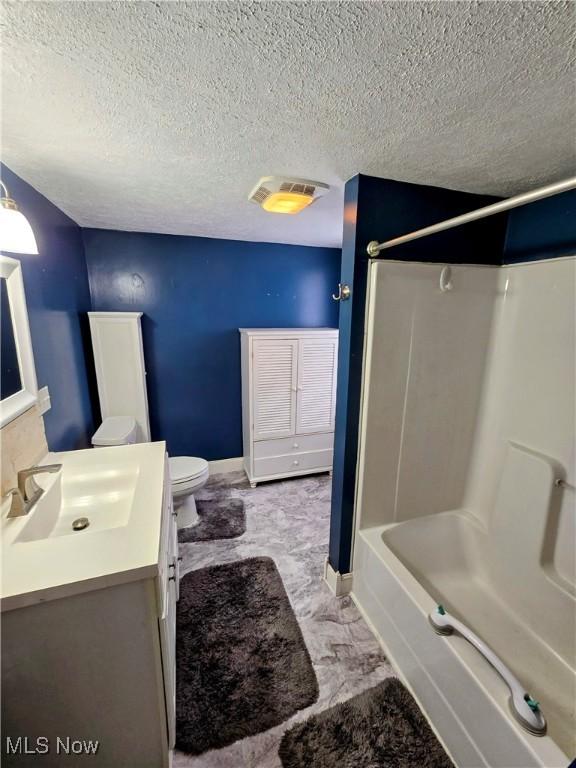 bathroom featuring bathtub / shower combination, visible vents, toilet, vanity, and a textured ceiling