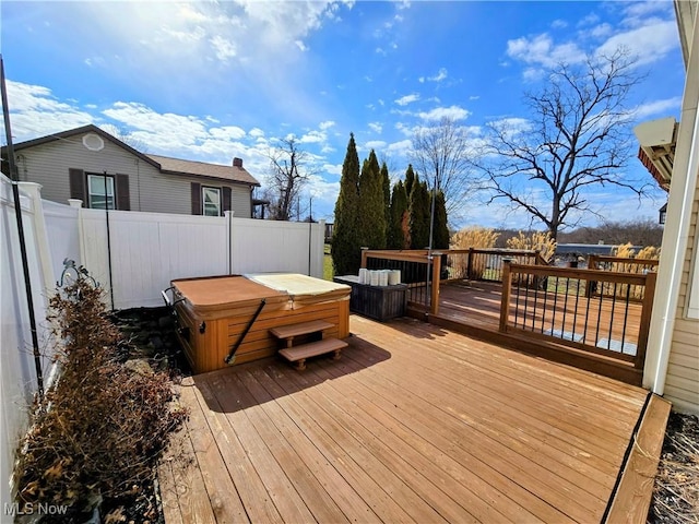 deck with a hot tub and fence