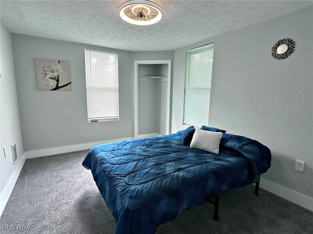 bedroom with visible vents, baseboards, a textured ceiling, carpet flooring, and a closet