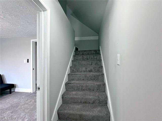 stairs with carpet, vaulted ceiling, a textured ceiling, and baseboards