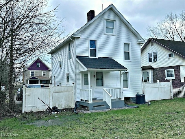 back of house with central AC unit, a chimney, fence, and a yard