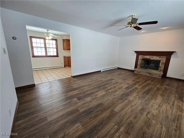 unfurnished living room with a glass covered fireplace, a baseboard heating unit, wood finished floors, and ceiling fan