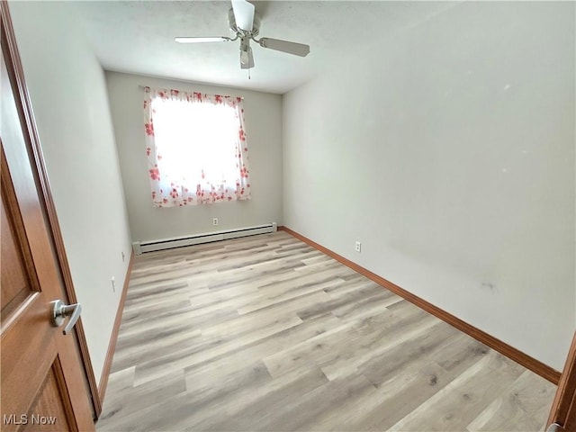 unfurnished room featuring baseboard heating, light wood-style flooring, and baseboards