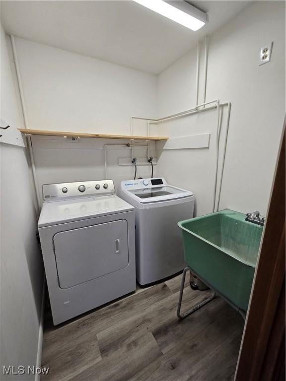 washroom featuring a sink, wood finished floors, laundry area, and washer and clothes dryer