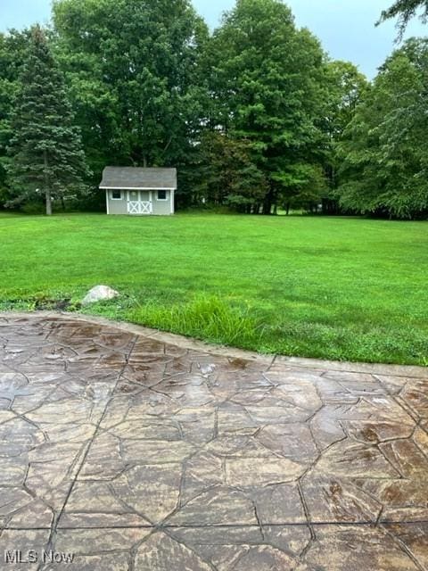 view of yard with an outbuilding, a storage shed, and a patio