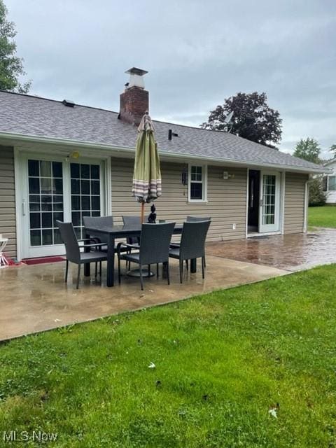 rear view of property with a yard, a chimney, and a patio