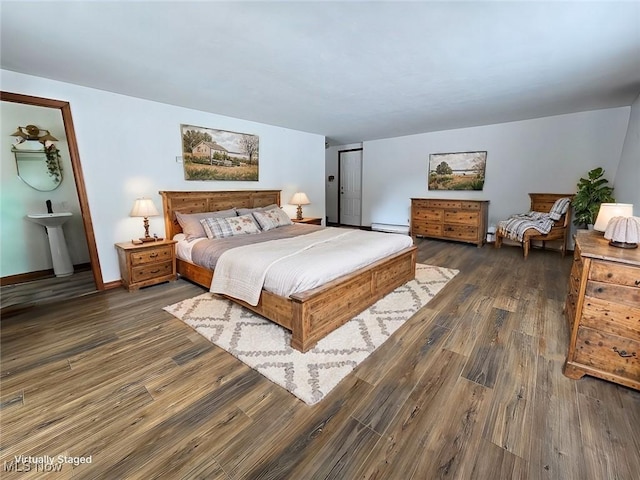 bedroom featuring a sink, baseboards, baseboard heating, and dark wood finished floors