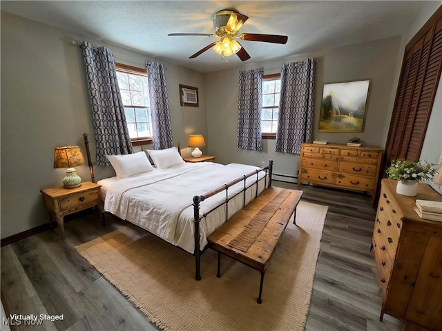 bedroom featuring baseboards, ceiling fan, baseboard heating, wood finished floors, and a closet