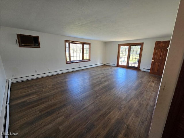 empty room featuring a wealth of natural light, baseboard heating, and dark wood-style flooring