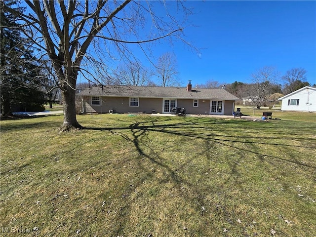 rear view of property with a yard, a patio area, and a chimney