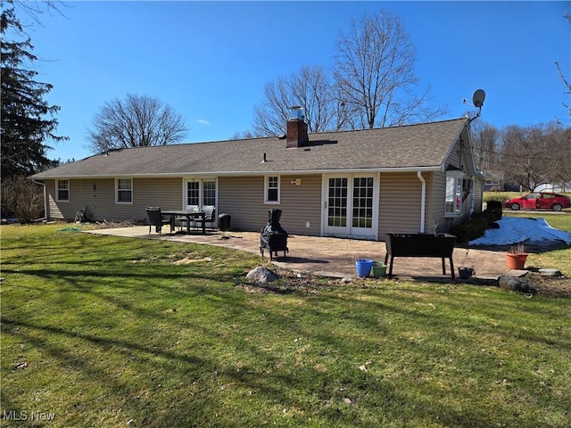 back of house featuring a lawn, a chimney, and a patio