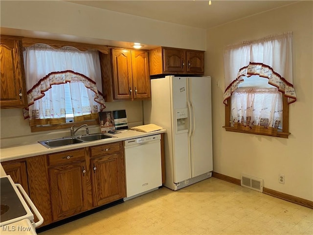 kitchen with white appliances, a sink, visible vents, light countertops, and light floors