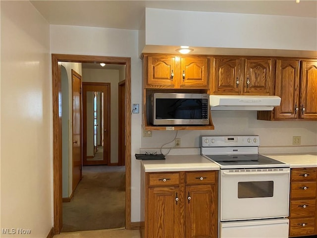 kitchen featuring white electric range oven, brown cabinetry, stainless steel microwave, light countertops, and under cabinet range hood