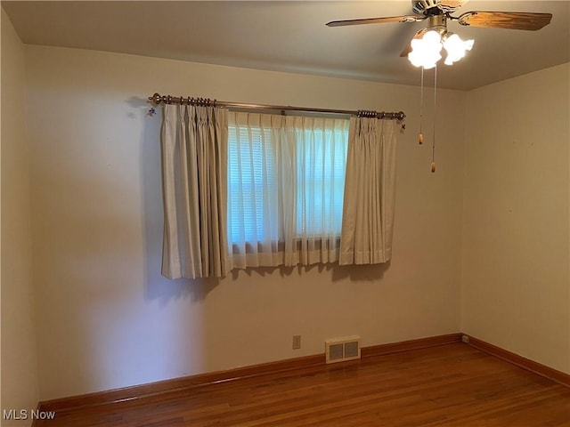 spare room featuring visible vents, ceiling fan, baseboards, and wood finished floors