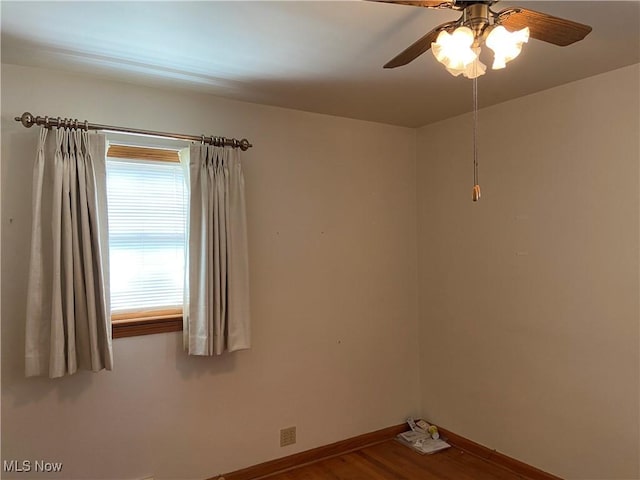 spare room with a ceiling fan, baseboards, and wood finished floors