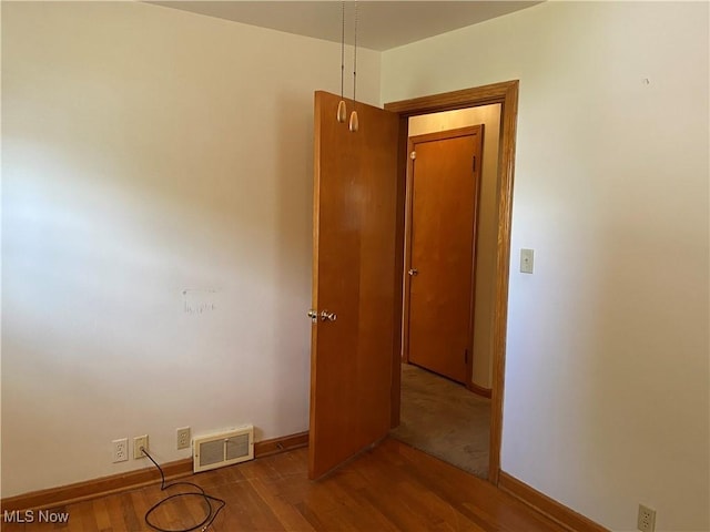 unfurnished room with baseboards, visible vents, and wood finished floors