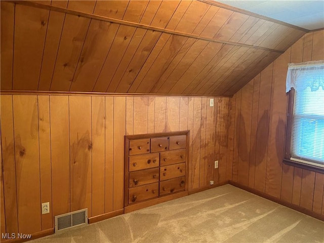 additional living space with carpet floors, lofted ceiling, visible vents, wood ceiling, and wooden walls