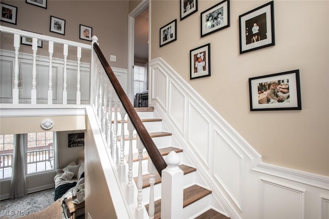 stairs with a decorative wall and wainscoting