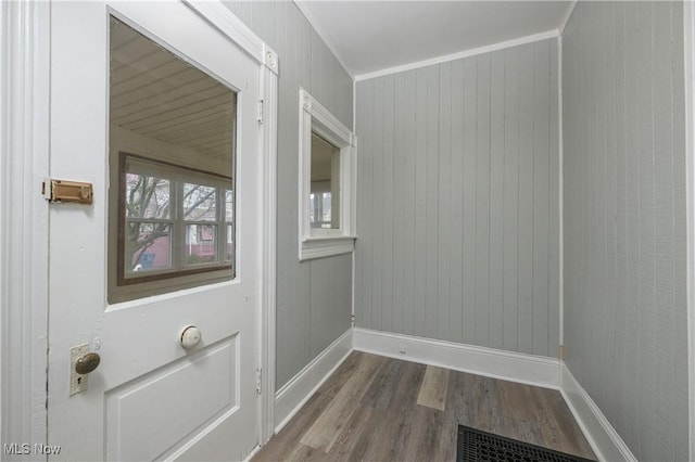 doorway featuring crown molding, wood finished floors, visible vents, and baseboards