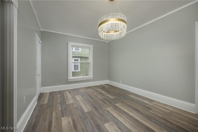 unfurnished room featuring a notable chandelier, crown molding, baseboards, and dark wood-type flooring