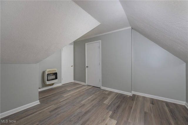 bonus room featuring baseboards, lofted ceiling, dark wood-type flooring, heating unit, and a textured ceiling