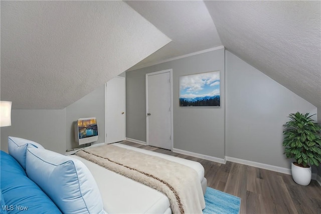 bedroom with baseboards, wood finished floors, heating unit, vaulted ceiling, and a textured ceiling