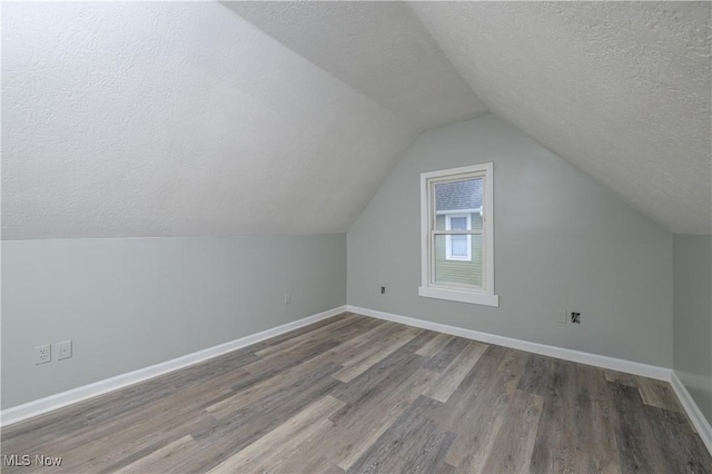 additional living space with a textured ceiling, wood finished floors, and baseboards