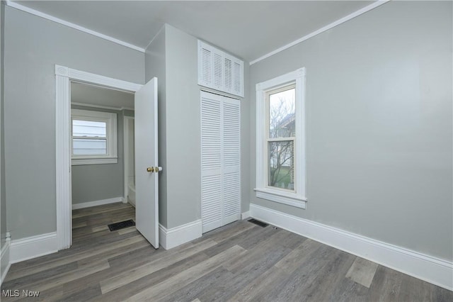 unfurnished bedroom with multiple windows, ornamental molding, and a closet