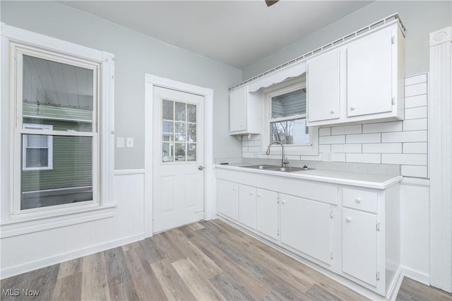 kitchen featuring light wood-style floors, light countertops, a sink, and white cabinetry