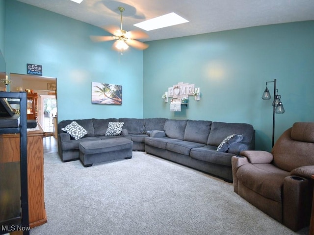 carpeted living area with a skylight, ceiling fan, and a towering ceiling