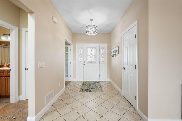 foyer entrance featuring light tile patterned floors, baseboards, and visible vents